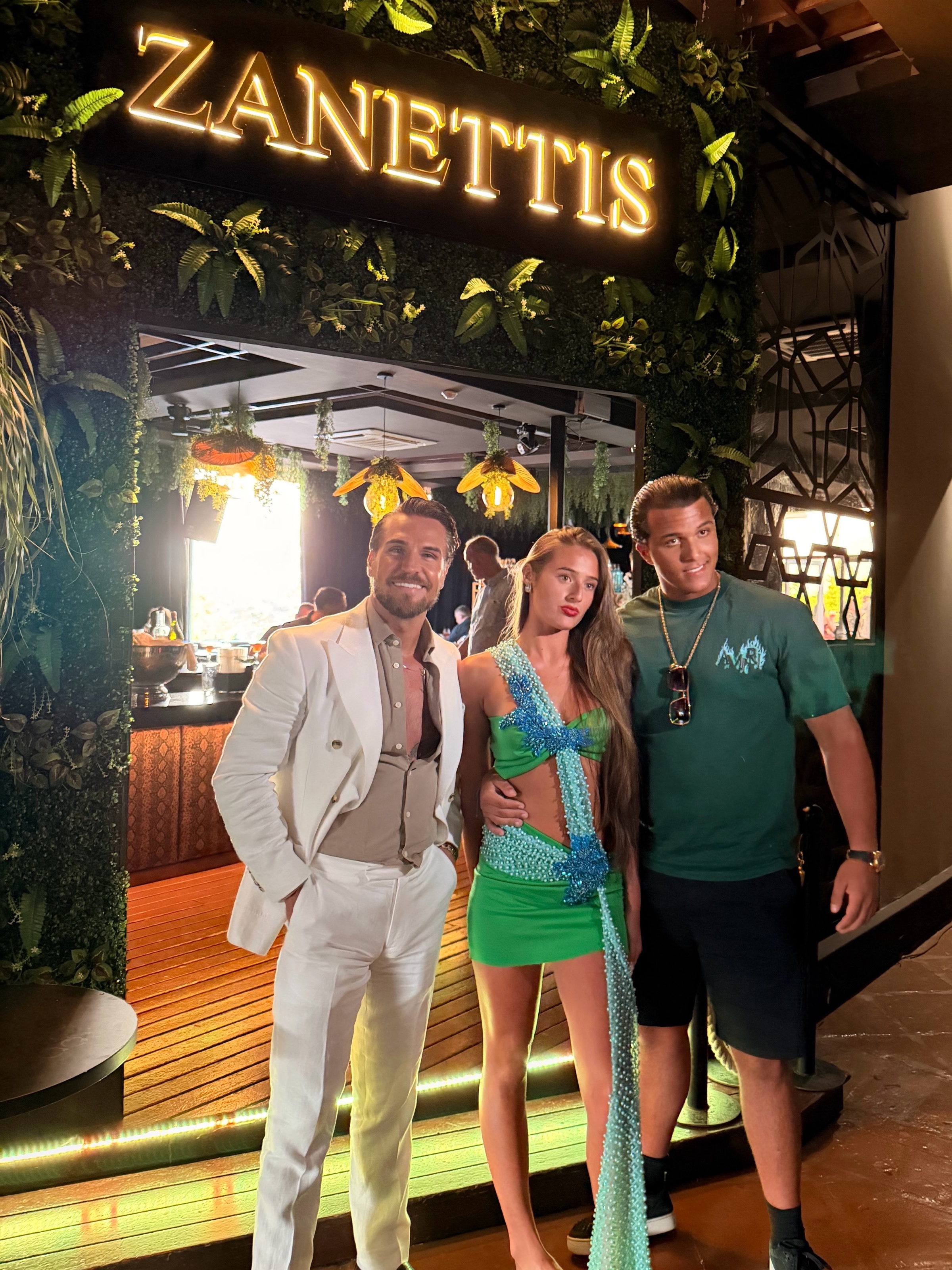The glowing gold ZANETTIS sign above the entrance, framed by a living green wall